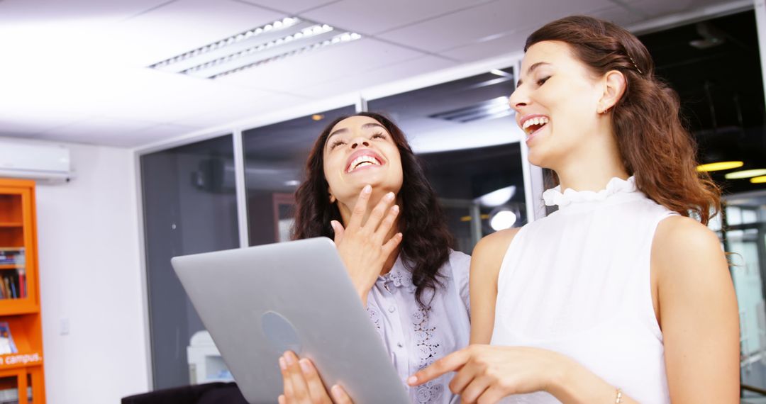 Two Women Laughing and Collaborating in Modern Office - Free Images, Stock Photos and Pictures on Pikwizard.com