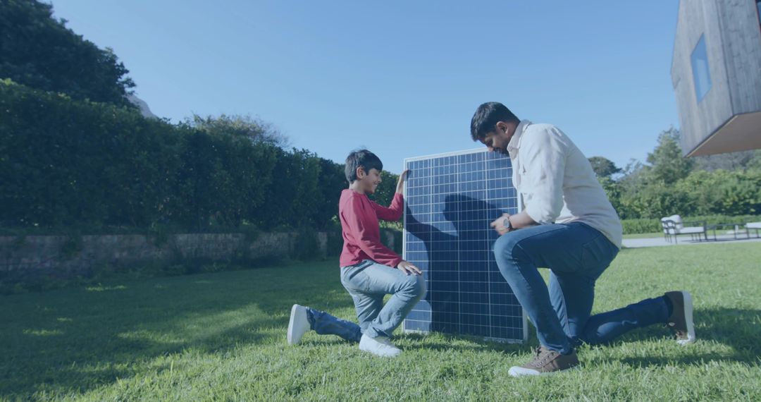 Father and son installing solar panel in backyard, learning about renewable energy
