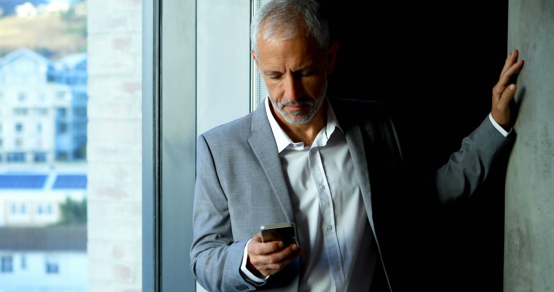 Senior Businessman Checking Phone in Modern Office - Free Images, Stock Photos and Pictures on Pikwizard.com