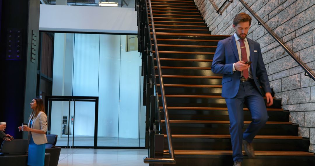 A Caucasian businessman in a suit is focused on his phone while descending stairs, with copy space - Free Images, Stock Photos and Pictures on Pikwizard.com