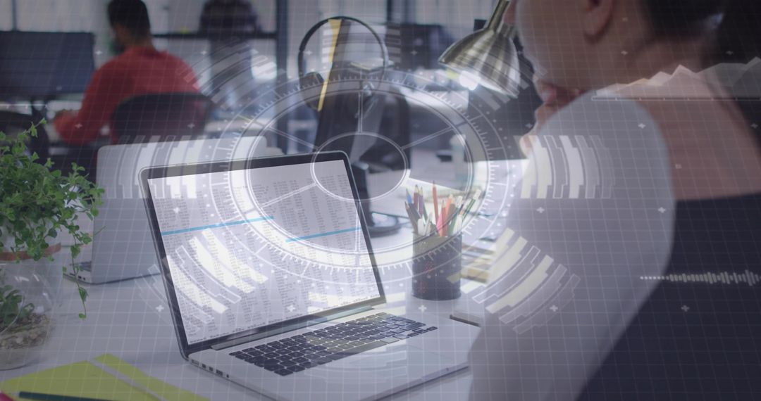 Laptop Displaying Spreadsheet with Futuristic HUD Overlay in Modern Open Office Workspace