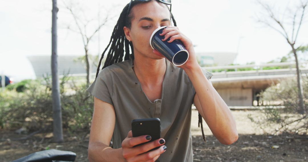 Fashionable biracial man with dreadlocks using smartphone and drinking coffee - Free Images, Stock Photos and Pictures on Pikwizard.com
