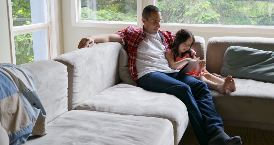 Father and Daughter Relaxing on Couch with Tablet in Living Room - Free Images, Stock Photos and Pictures on Pikwizard.com