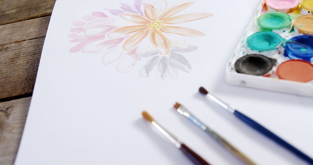 An artist or hobbyist is creating a watercolor flower painting with colorful art supplies. - Free Images, Stock Photos and Pictures on Pikwizard.com