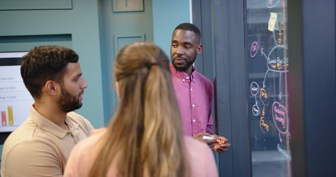 Diverse Team Brainstorming Business Strategies on Glass Board