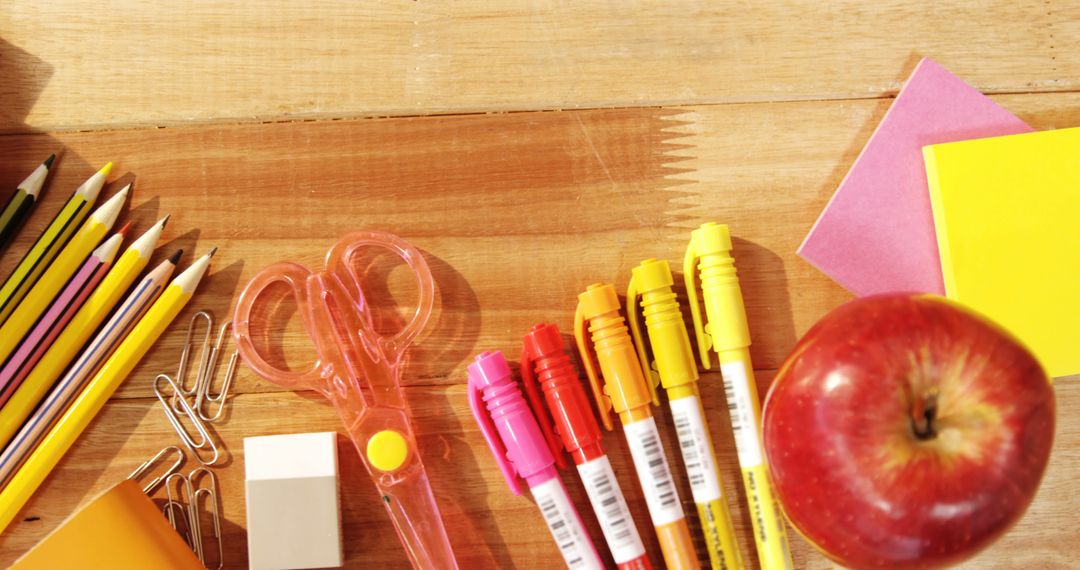 Assorted School Supplies and Apple on Wooden Desk