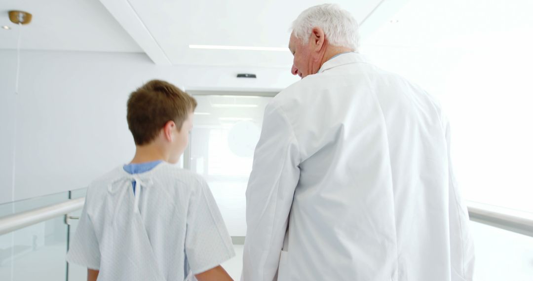 Senior Doctor Escorting Young Patient in Hospital Hallway - Free Images, Stock Photos and Pictures on Pikwizard.com