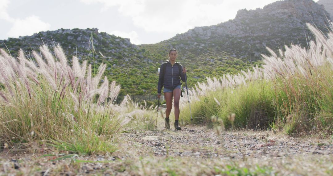 African American Woman Hiking with Trekking Poles in Scenic Mountains