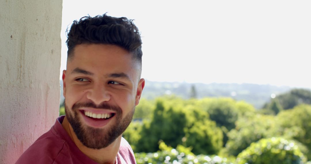 Smiling Man Enjoying Scenic Balcony View Under Sunlit Sky