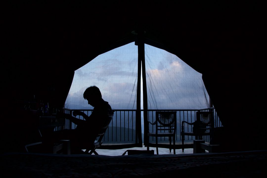 Silhouetted Person Relaxing on Balcony at Twilight - Free Images, Stock Photos and Pictures on Pikwizard.com