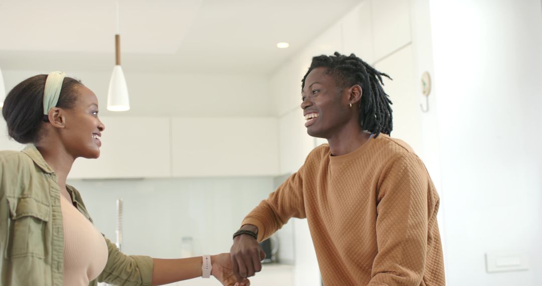 African American Couple Smiling and Clasping Hands in Bright Modern Kitchen
