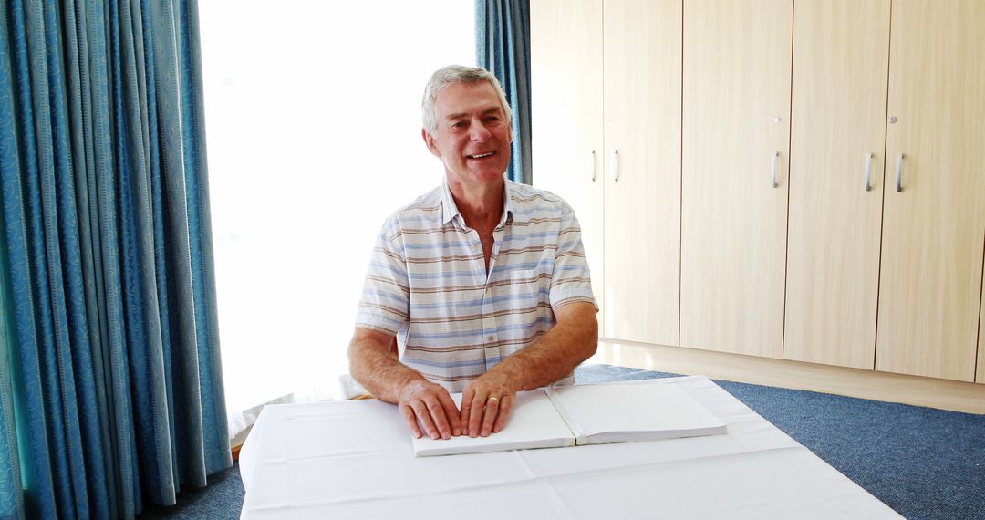 Smiling Elderly Man Reading Braille in Bright Room - Free Images, Stock Photos and Pictures on Pikwizard.com