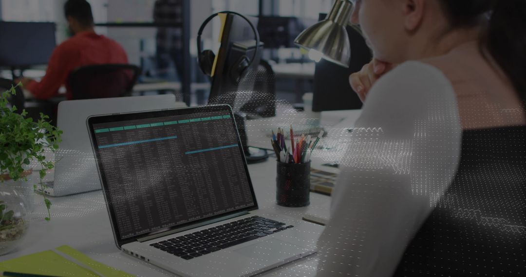 Woman studying laptop terminal in coworking office coding data with headphones