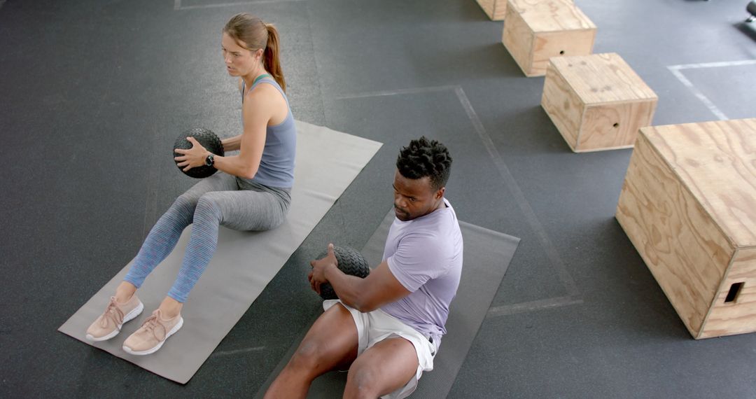 Diverse Athletes Strengthening Core with Medicine Balls at Gym