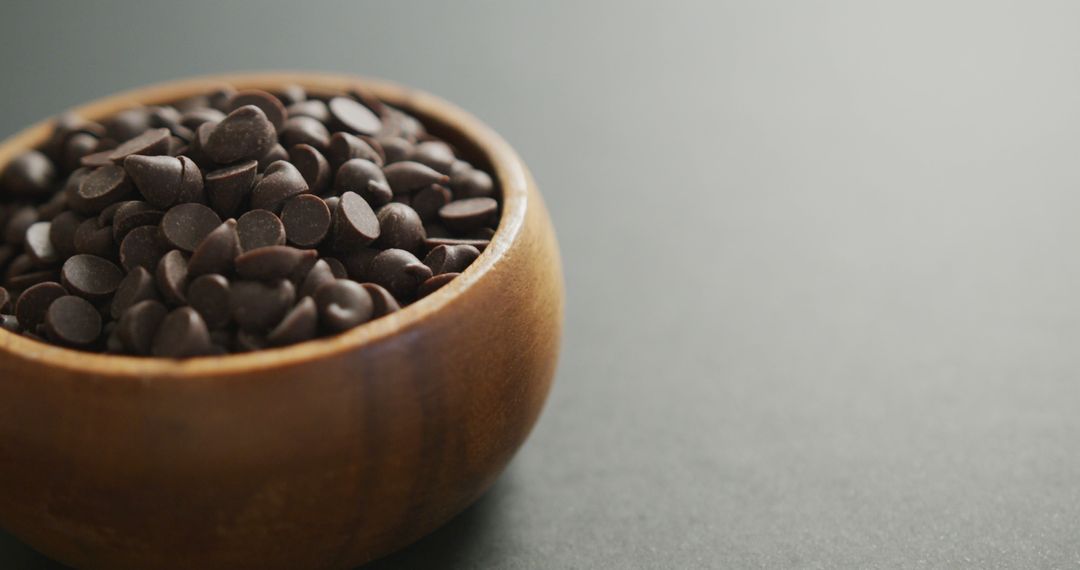 Wooden bowl filled with dark chocolate chips on gray background - Free Images, Stock Photos and Pictures on Pikwizard.com