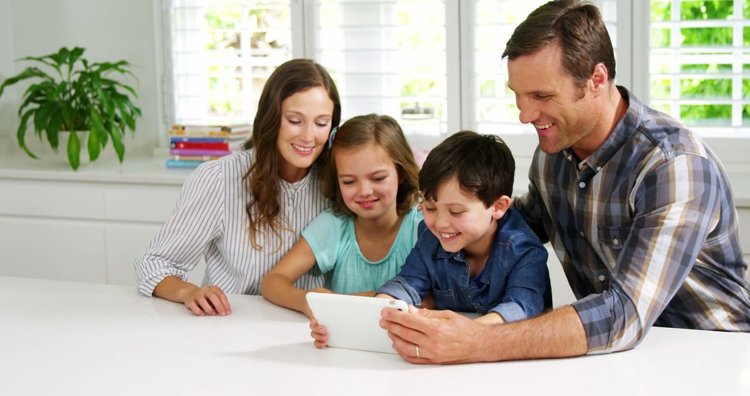 Happy Family Sitting at Kitchen Table Using Tablet Together - Free Images, Stock Photos and Pictures on Pikwizard.com