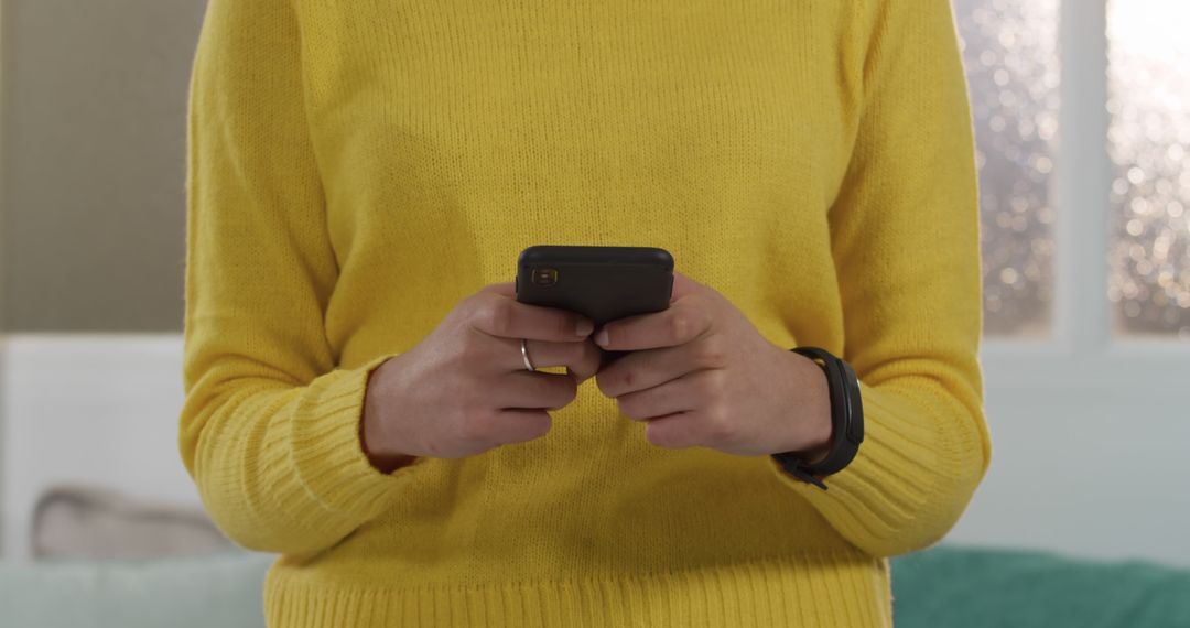 Person Wearing Yellow Sweater Using Smartphone Indoors - Free Images, Stock Photos and Pictures on Pikwizard.com