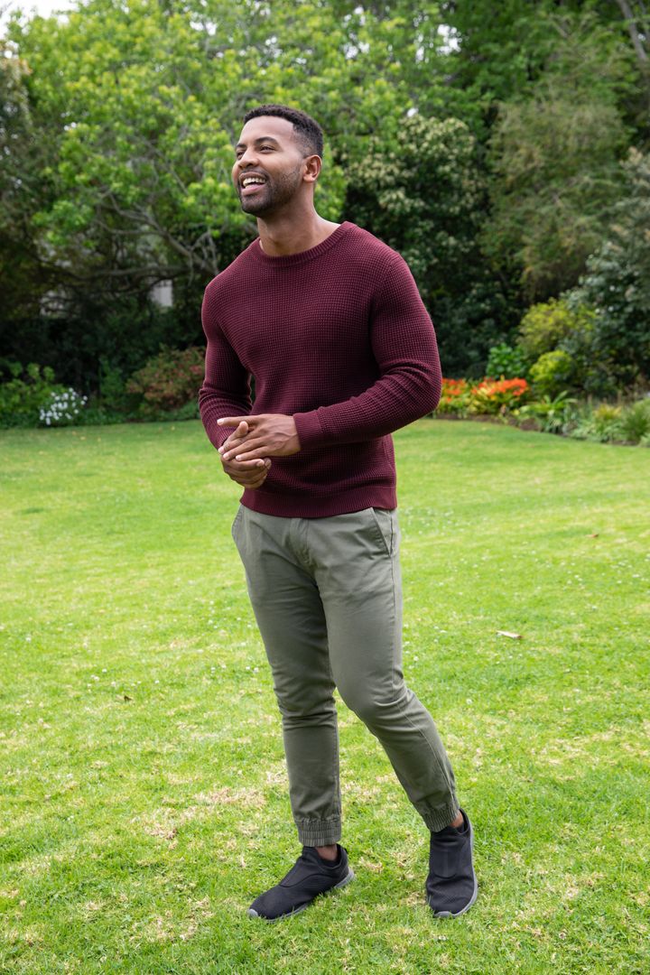 Man in Maroon Sweater Enjoying Tranquil Green Backyard