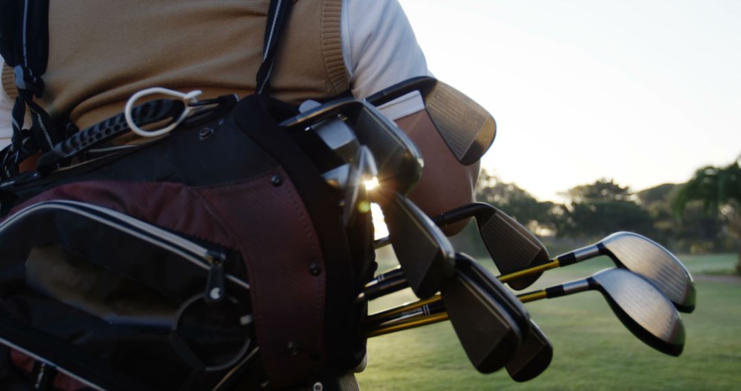 Golfer Carrying Clubs on Golf Course During Sunrise with Green Landscape - Free Images, Stock Photos and Pictures on Pikwizard.com