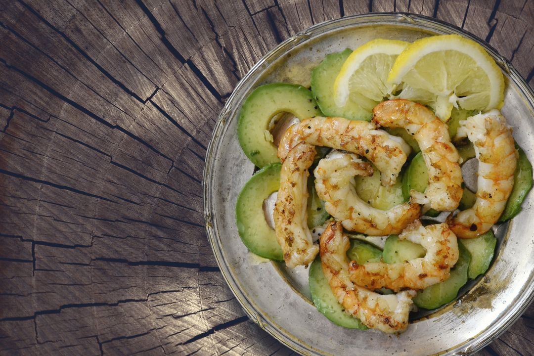 Grilled Prawns with Avocado and Lemon Garnish on Rustic Wood