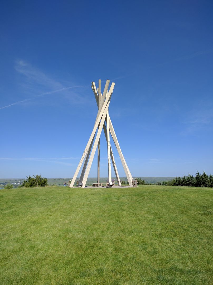 Tall Sculpture on Green Grassy Hill with Clear Blue Sky - Free Images, Stock Photos and Pictures on Pikwizard.com