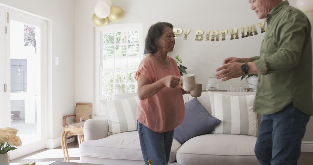 Elderly Couple Setting Up Birthday Decorations at Home