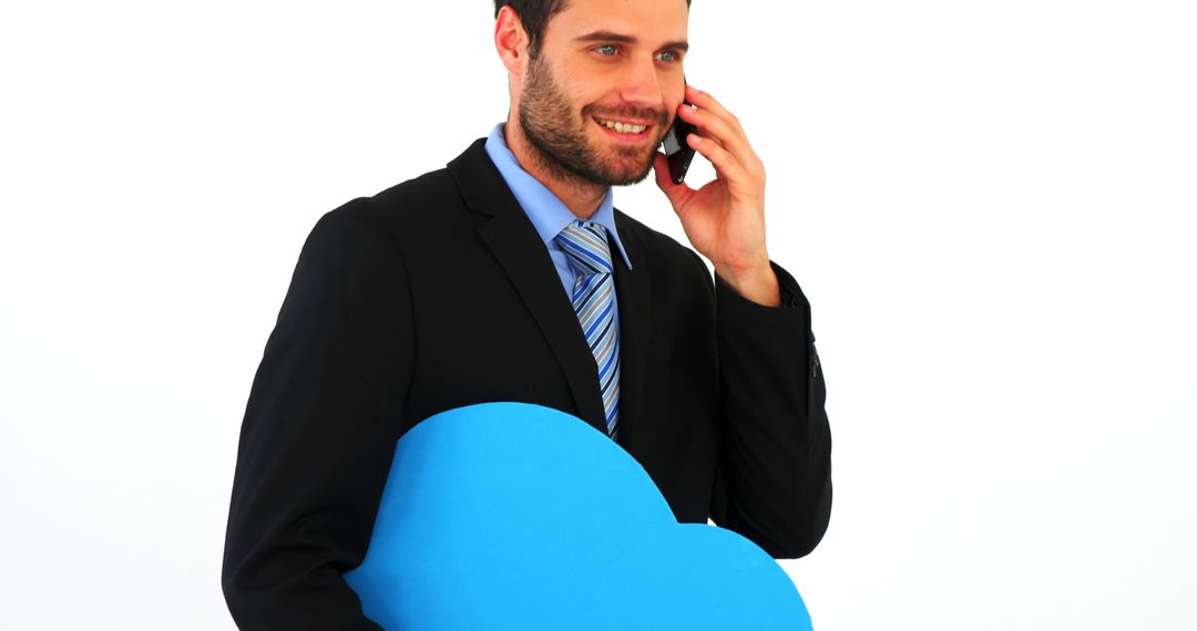 Businessman Holding Blue Cloud Cutout while Talking on Mobile Phone - Free Images, Stock Photos and Pictures on Pikwizard.com