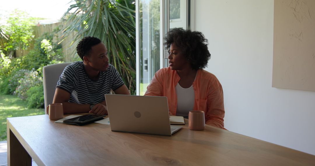 Couple Discusses Plans with Laptop and Coffee at Home