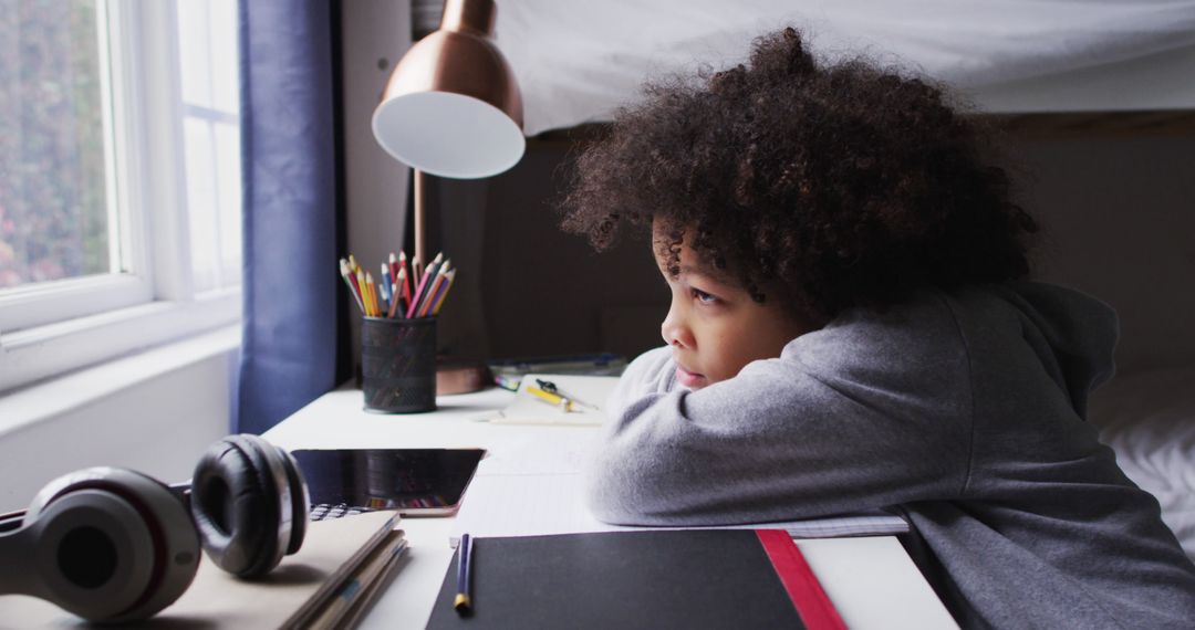Thoughtful Child by Desk Looking Out Window at Home