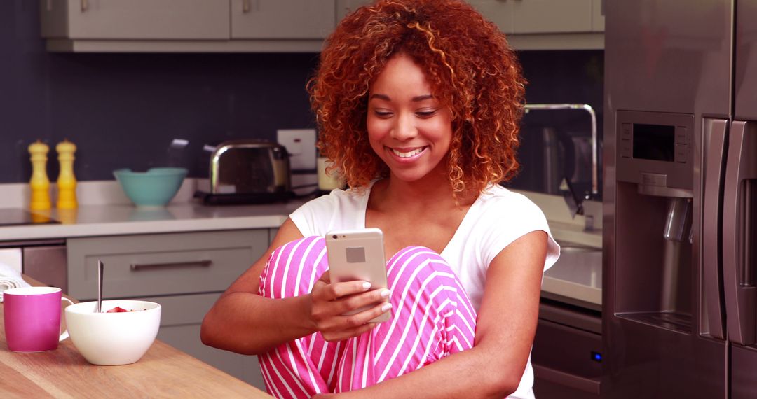 Woman Relaxing in Kitchen Using Smartphone in Morning - Free Images, Stock Photos and Pictures on Pikwizard.com