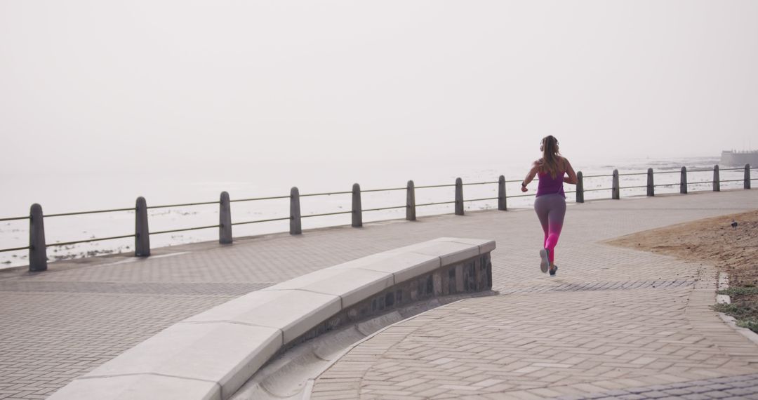 Woman Jogging on Coastal Pathway During Foggy Morning - Free Images, Stock Photos and Pictures on Pikwizard.com