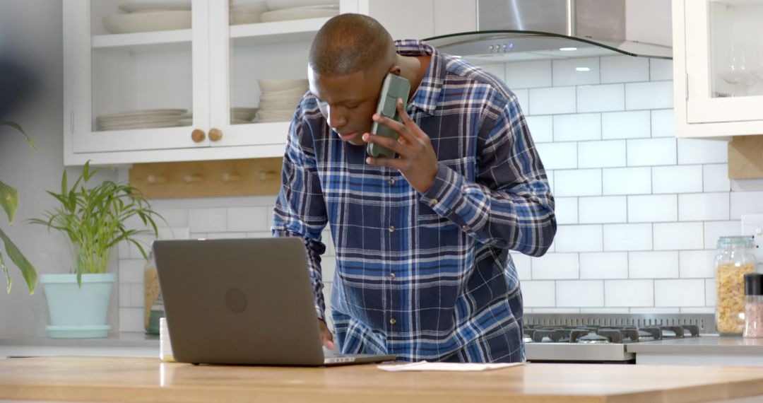 African American Man Multitasking in Kitchen with Laptop and Phone - Free Images, Stock Photos and Pictures on Pikwizard.com