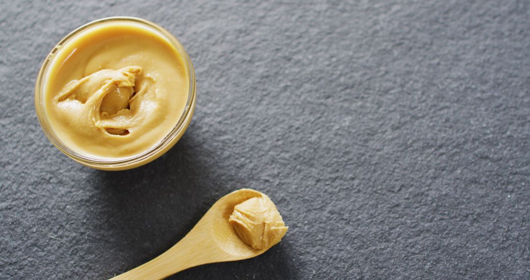 Smooth Peanut Butter in Jar and Spoon on Slate Background