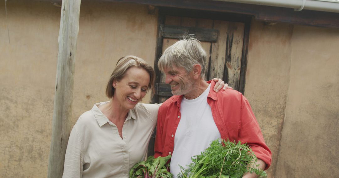 Senior Caucasian Couple Embracing While Harvesting Vegetables