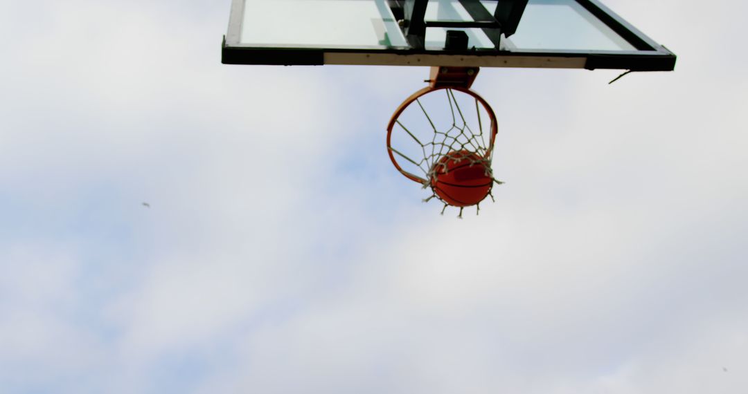 Basketball swishing through hoop against clear sky - Free Images, Stock Photos and Pictures on Pikwizard.com