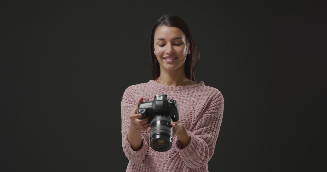 Smiling Woman Holding Camera Against Black Background - Free Images, Stock Photos and Pictures on Pikwizard.com