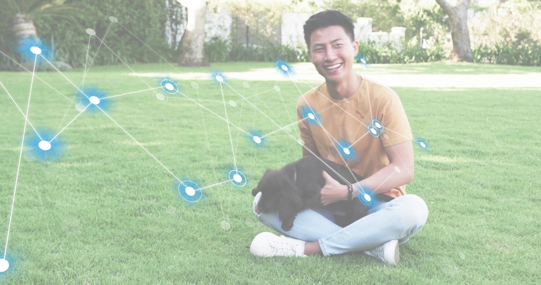 Smiling young man sitting on grass with black dog and network overlay suggesting connection