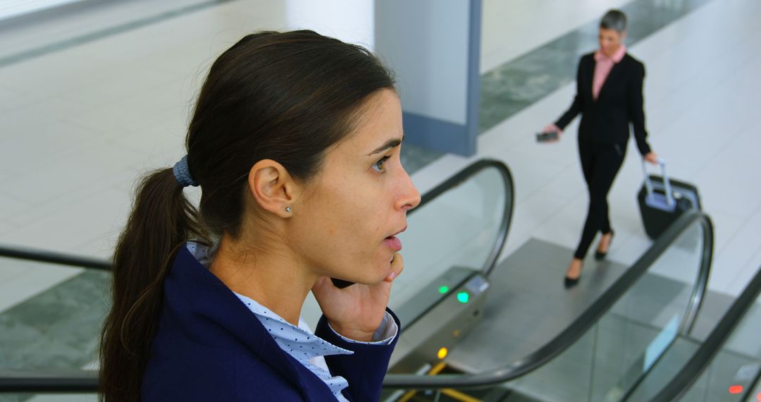 Businesswoman Talking on Phone While Descending Escalator in Modern Airport Terminal - Free Images, Stock Photos and Pictures on Pikwizard.com