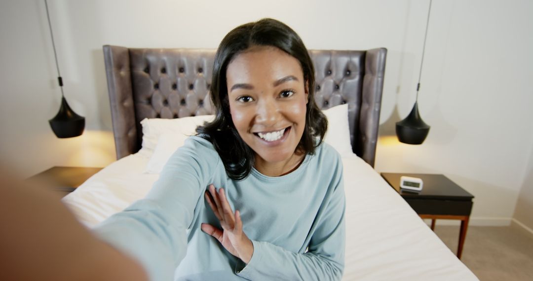 Smiling Woman Engaging in Online Session in Modern Bedroom