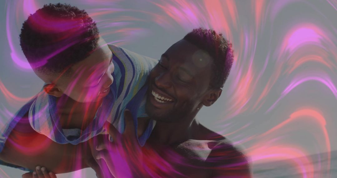 Father Lifting Son Among Vibrant Pink Light Patterns at Beach