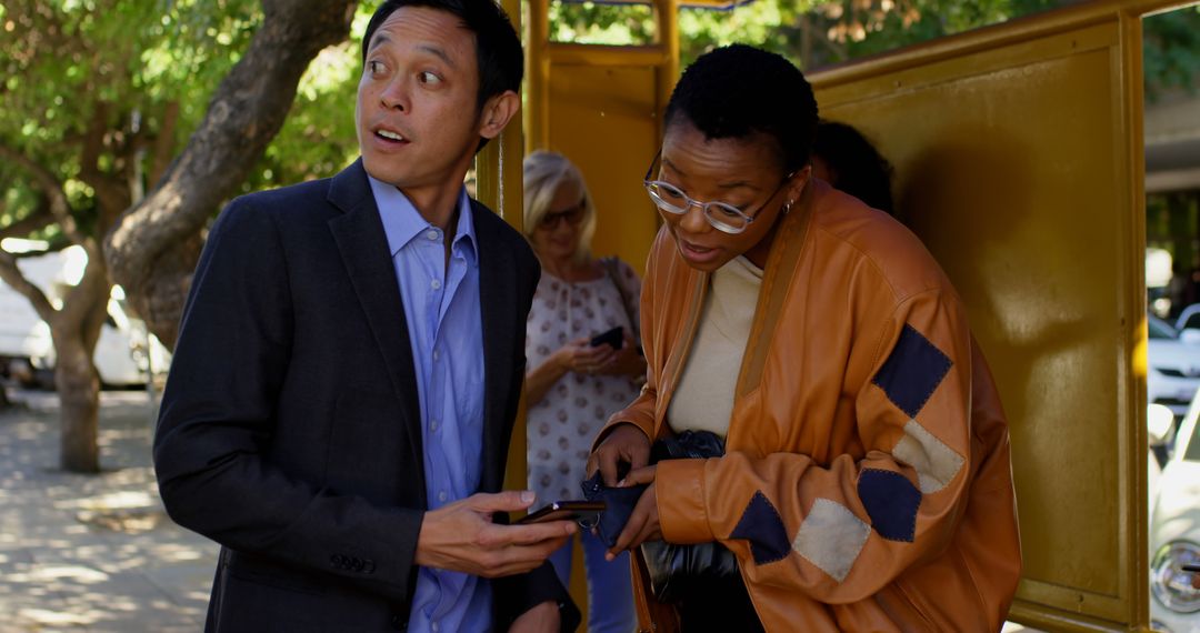 People Engaged in Conversation Using Smartphone at Bustling City Bus Stop