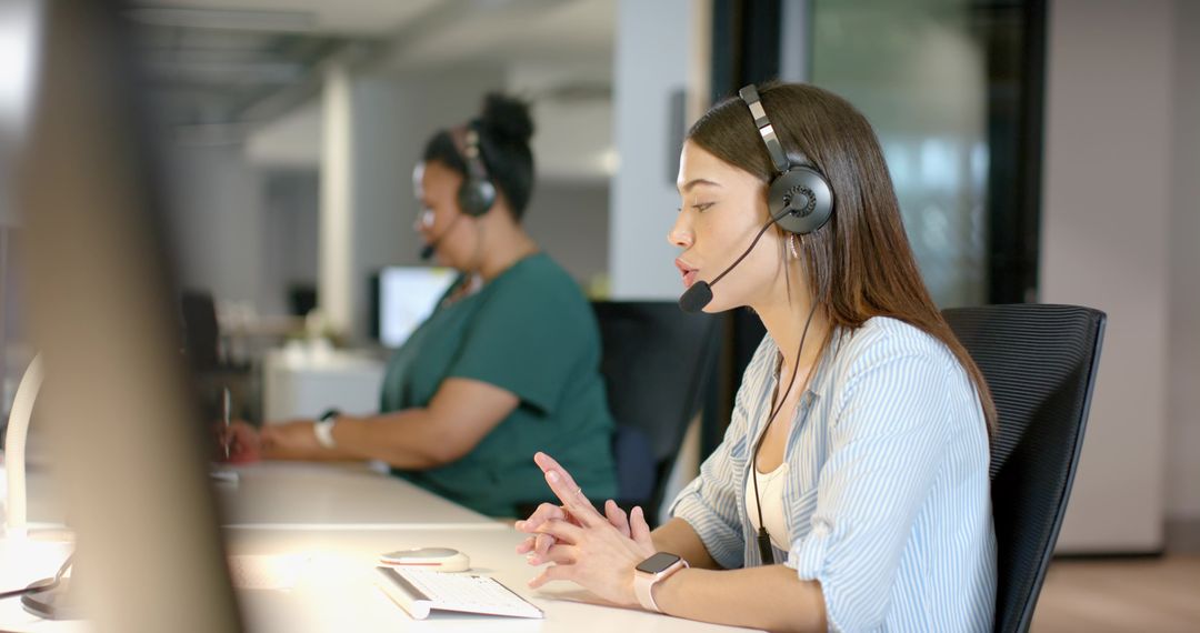 Female customer support agents wearing headsets assisting callers in open-plan office