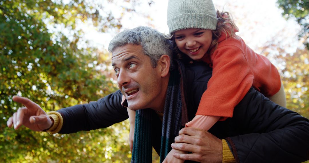 Joyful Father Piggybacking Young Daughter During Autumn Outdoor Adventure - Free Images, Stock Photos and Pictures on Pikwizard.com