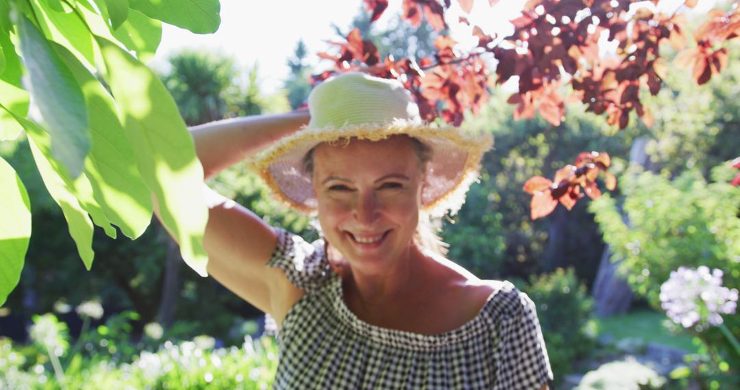 Portrait of happy caucasian senior woman walking in garden wearing sunhat and smiling in the sun - Free Images, Stock Photos and Pictures on Pikwizard.com