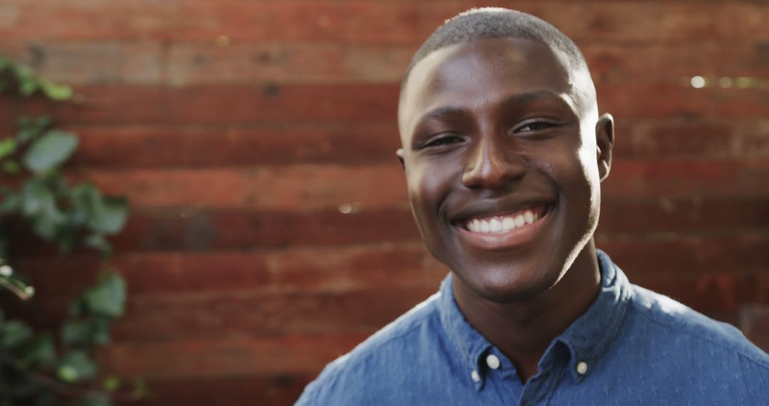 Smiling Young African American Man Standing Against Wooden Background - Free Images, Stock Photos and Pictures on Pikwizard.com