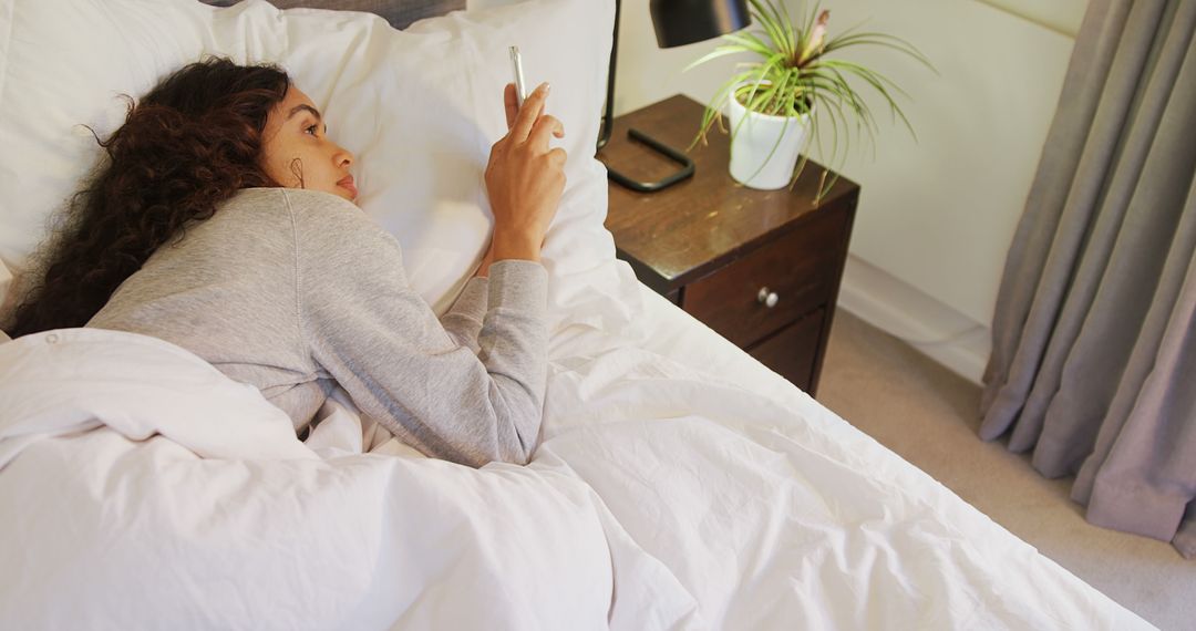 Young woman using smartphone in bed in cozy bedroom - Free Images, Stock Photos and Pictures on Pikwizard.com