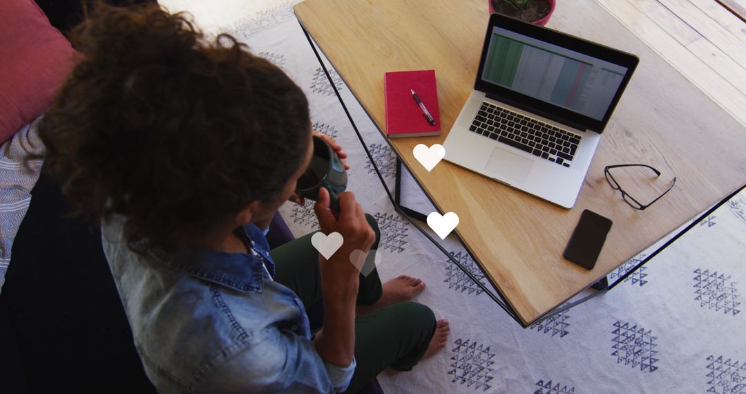 Biracial Woman Using Laptop with Heart Icons Overhead
