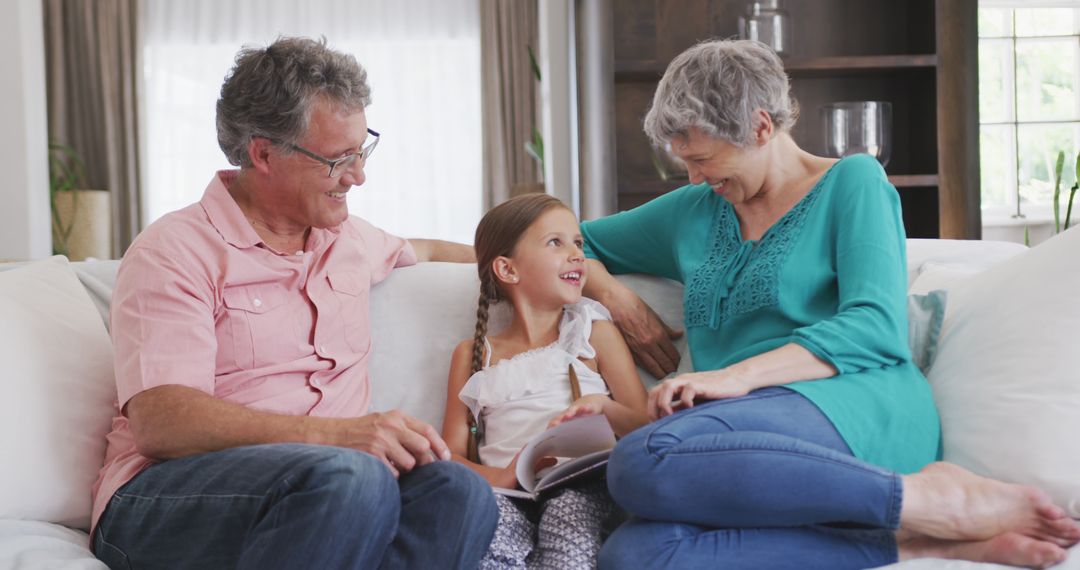 Smiling Grandparents and Granddaughter Reading Book Together at Home - Free Images, Stock Photos and Pictures on Pikwizard.com