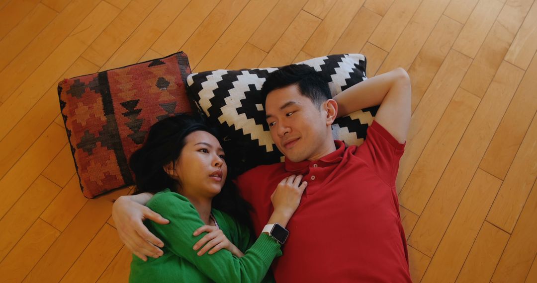 Young Asian Couple Relaxing on Wooden Floor with Cushions - Free Images, Stock Photos and Pictures on Pikwizard.com