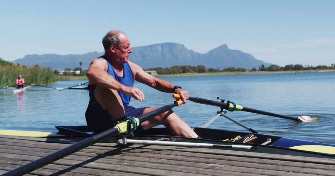 Senior Man Preparing for Rowing in Mountainous Lake Area - Free Images, Stock Photos and Pictures on Pikwizard.com